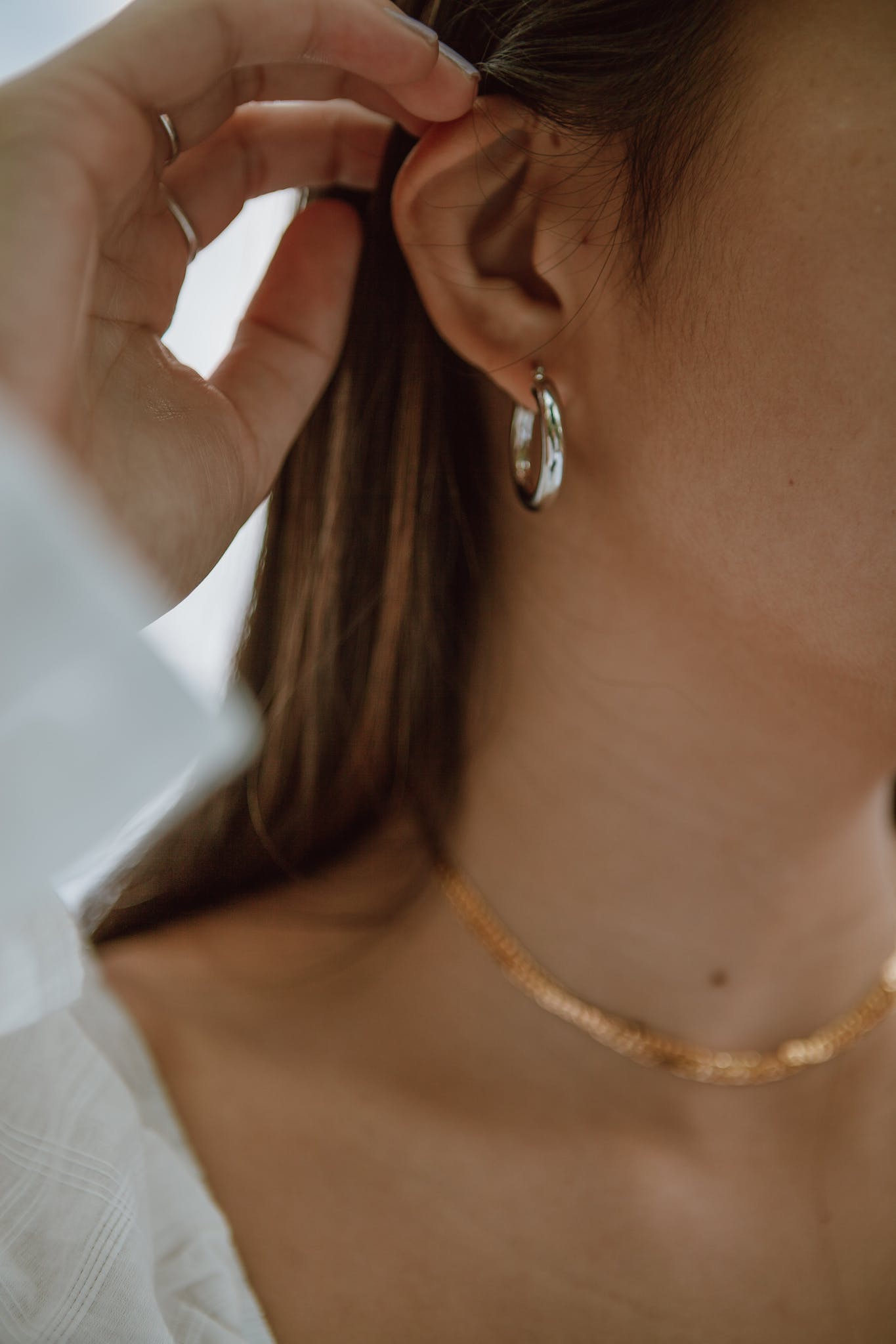 Crop woman with gold earings demonstrating hand with manicure and precious ring on ring finger