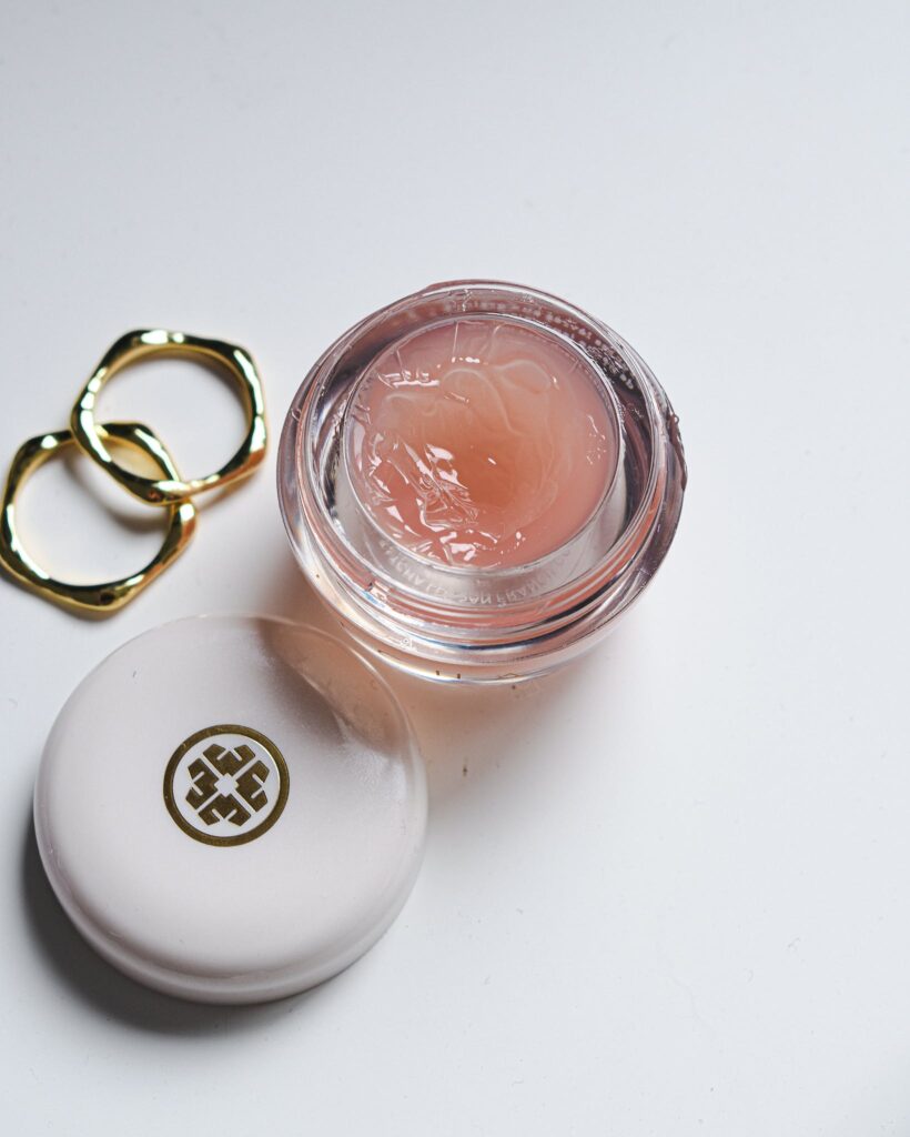 Gold Rings and Cosmetic Gel in a Jar against White Background